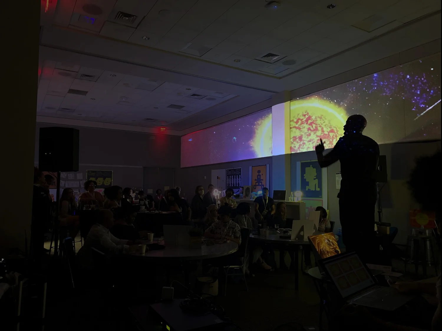 Audience watching a large projected artwork during an evening exhibition event.