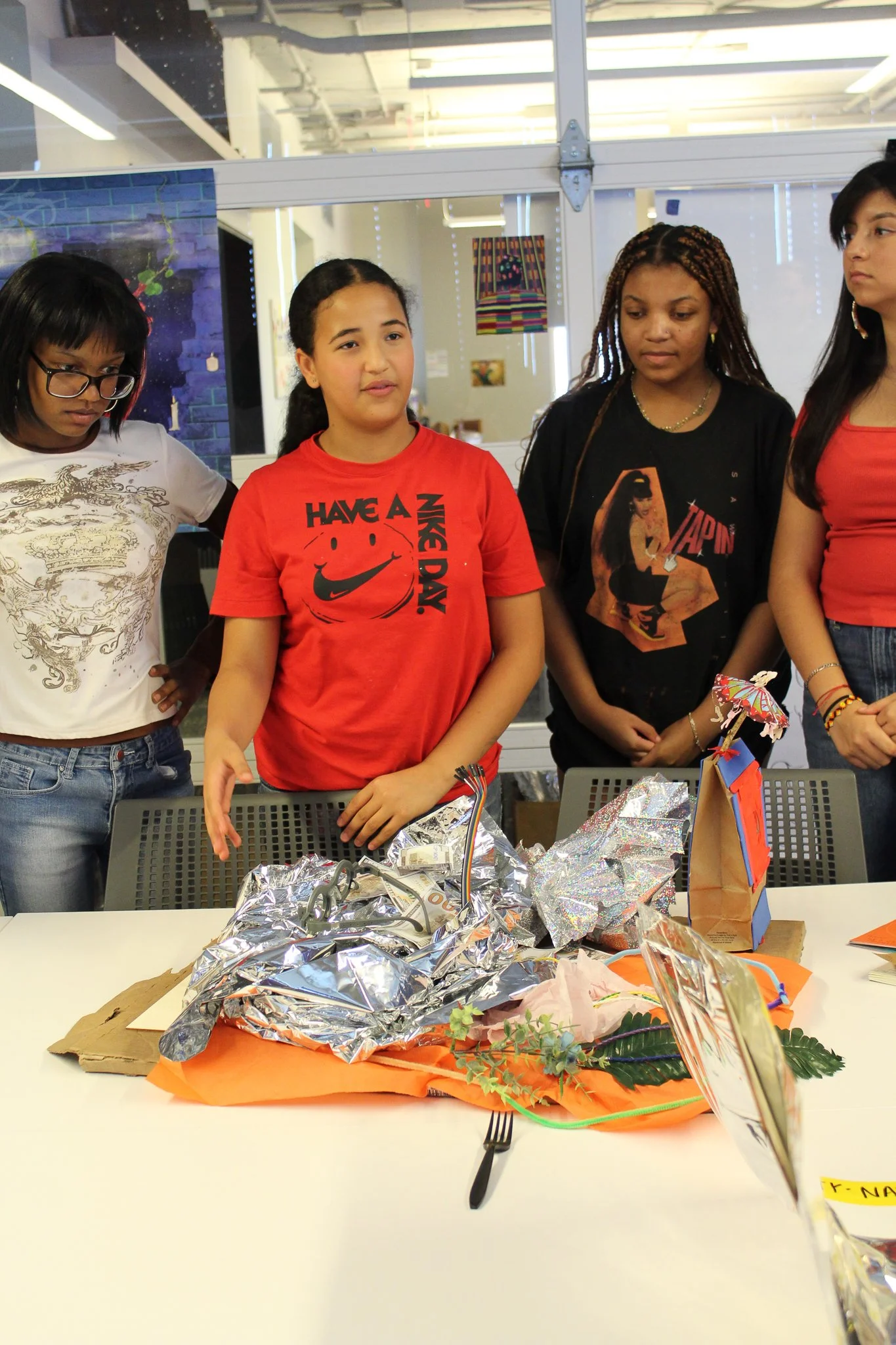 Participants at a workshop table looking at printed materials and foil